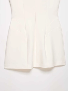 Detailed view of white sleeveless dress showing curved seams and side pocket texture