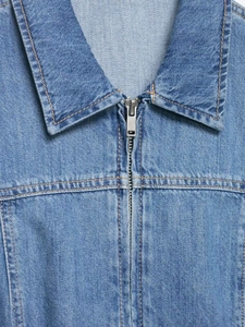 Detail of light blue denim shirt with silver zipper and orange contrast stitching