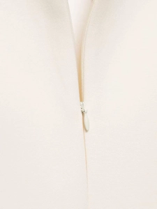 Detail showing the invisible zipper closure on a white sleeveless dress with textured fabric