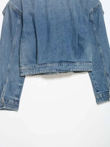 Detailed view of the back hem and cuff stitching on a classic blue denim jacket