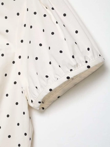 Close-up of polka dot puff sleeve detail with delicate pleated cuffs on a white shirt