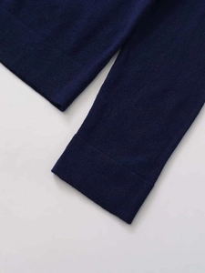 Dettaglio del cardigan in maglia blu scuro con polsini a costine e cuciture rifinite