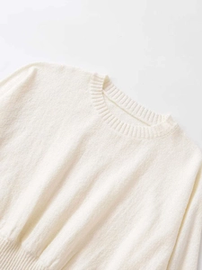 Detail shot of elegant white knit sweater showing ribbed crew neck and soft fabric texture