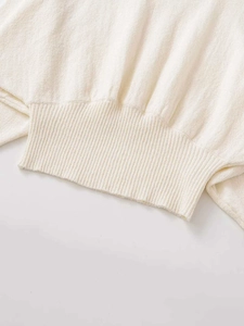 Close-up of elegant cream white knit sweater showing detailed ribbed hem and soft texture