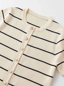 Dettaglio del cardigan in maglia crema a righe nere e bottoni dorati con ancora