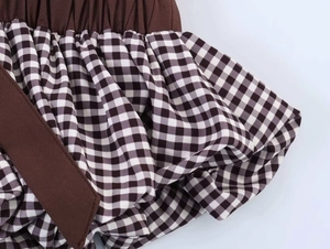 Macro detail of elastic pleated brown fabric joined with black gingham checkered skirt