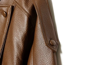 Detailed close-up of brown faux leather jacket texture with high-quality stitching and buttons