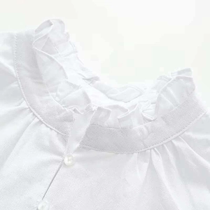 Detail shot of white ruffle stand collar and button closure on short sleeve blouse