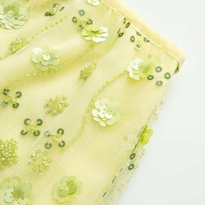 Détail macro des broderies florales en paillettes 3D et perles sur jupe en tulle