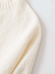Close-up of cream white knit sweater showing ribbed cuffs and fine needlework texture