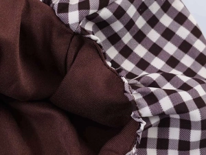 Detailed close-up showing the plaid fabric and brown plain weave material with ruffles