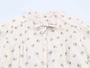 Detail of floral print blouse with neck bow tie and pleated shoulder stitching