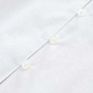 Close-up of white cotton linen shirt showing textured fabric and neat button detail