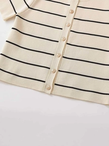 Dettaglio del cardigan in maglia a righe nere con bottoni dorati ornamentali