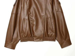 Detail of caramel brown PU leather jacket featuring elastic hem and lychee grain texture