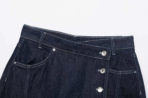 Detail of dark blue crossover waist denim shorts with metal buttons and white contrast stitching