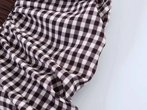 Detail shot of black and white gingham shirt featuring ruffled texture and pleated accents