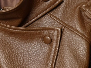 Detail of brown PU leather biker jacket showing collar stitching and textured surface