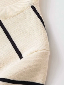 Dettaglio macro del tessuto a maglia crema con strisce nere e cuciture pregiate