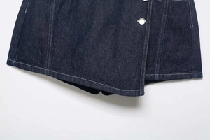 Detail view of dark blue denim dress with white contrast stitching and metal buttons