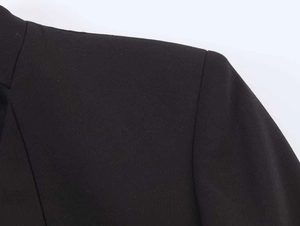 Detailed macro view of the padded shoulder and woven fabric of a black tailored blazer