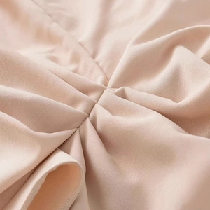 Sleeveless pleated beige midi dress featuring elegant ruched knit fabric texture