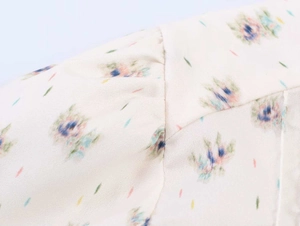 Close-up detail of floral print pattern and high-quality stitching on white fabric blouse