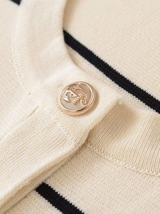 Dettaglio del bottone dorato con ancora su tessuto a maglia a righe beige