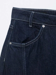 Detailed close-up of dark blue denim fabric with contrast stitching and metal rivets