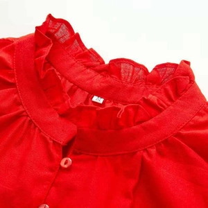 Detailed close-up of red ruffled stand collar with matching buttons and soft texture
