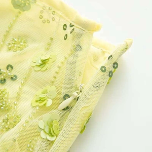 Détail de jupe en mesh jaune avec sequins floraux turquoise, perles et zip invisible
