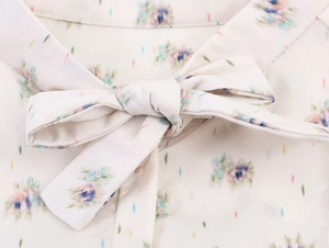Close-up of floral print shirt featuring a delicate bow tie detail at the neckline