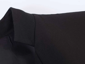 Close-up detail of the lapel and shoulder seam on a tailored black suit blazer