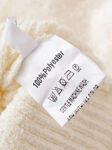 Detailed view of the wash label on a beige ribbed knit sweater made of 100% polyester