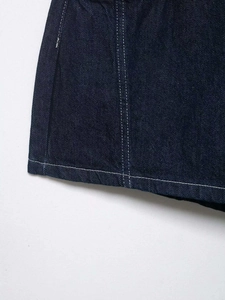 Detail of dark blue denim fabric with white contrast stitching and double-needle hems
