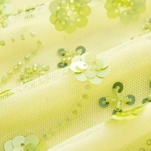 Vue macro de broderie florale 3D avec sequins et perles sur tissu tulle vert lime