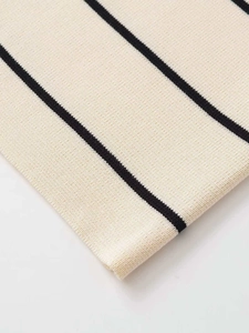 Dettaglio del tessuto a maglia color crema con strisce nere e trama dettagliata