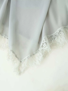 Dettaglio di tessuto georgette azzurro con raffinato bordo in pizzo bianco