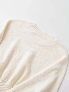 Detail view of the ribbed crewneck and knit texture on this cream-white long sleeve sweater