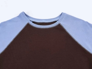 Detail of round neckline with flatlock stitching on blue and brown raglan sleeve t-shirt