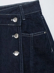 Detail of dark blue denim skirt with contrast stitching and metallic button closures