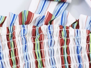 Close-up of colorful striped fabric with elastic smocking and ruffle trim detail