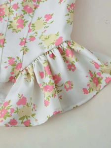 Close-up of white floral fabric with pink blossoms and elegant ruffle hem detail