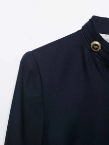 Detail of navy blue blazer collar with gold embossed crest button and twill texture