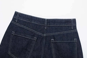 Detailed view of dark blue denim jeans with contrast white stitching and rear pockets