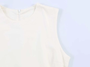 Detail view of cream sleeveless dress featuring a round neckline and rear zipper closure