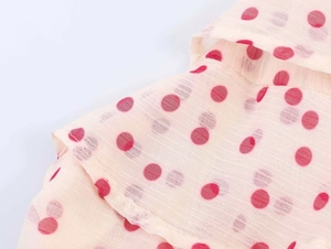 Close-up of beige georgette fabric with burgundy polka dots and ruffle detail