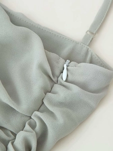 Dettaglio delle spalline regolabili e zip laterale sulla maglia a pieghe verde salvia