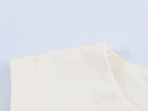 Close-up of the smooth stitching and soft knit fabric texture on an off-white dress