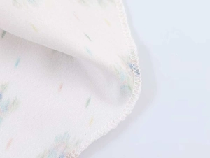 Detail of white fabric with colorful polka dot print and fine overlock stitching edges